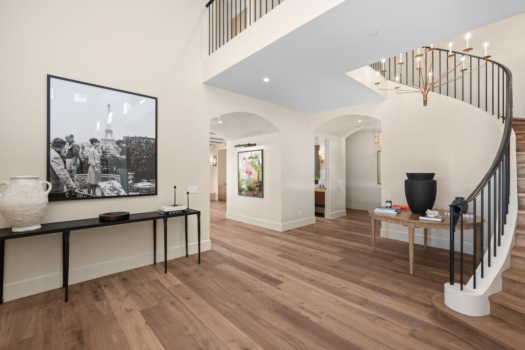 Modern foyer with wood flooring, black spiral staircase, and wall art on light-colored walls.